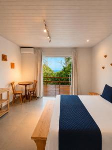 a bedroom with a bed and a table and a balcony at Shalon Adonai by Martinelli Lodge in Fernando de Noronha