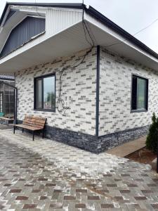 a building with a bench on a brick patio at Tunduk Lux House in Teploklyuchinskoye +21 photos