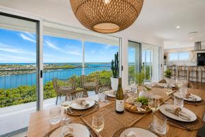 a dining room with a table with wine glasses at Lazy Days Penthouse - Opposite Shaws Bay - 180 Waterfront Views in East Ballina