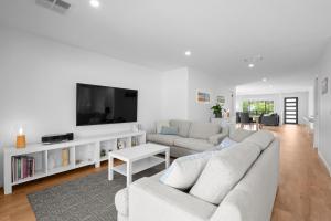 a white living room with a couch and a tv at Links Golf Retreat in Mansfield