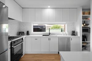 a white kitchen with white cabinets and a window at Links Golf Retreat in Mansfield