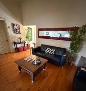 a living room with a black leather couch and a coffee table at Lotte's Cottage in Broken Hill