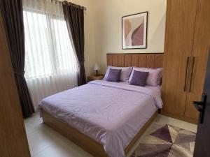 a bedroom with a bed with purple sheets and a window at Olympus House Meublé Kena in San Aparicio
