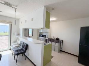 a kitchen with a counter and chairs in a room at ゲストハウス 華園 in Furano