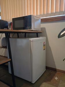 a desk with a microwave on top of a refrigerator at Baulkham Hills Deluxe King Room with Ensuite, Private Access & Air Con in Baulkham Hills