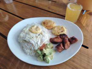 a white plate of food with rice and eggs and vegetables at Homestay Natural Paradise habitación 2 in San Cristóbal