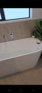 a white bath tub with a glass of wine and a plant at Kupe Boutique House with ensuite free wifi in Whitianga