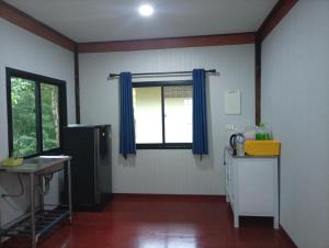 a kitchen with a refrigerator and a window with blue curtains at hadya home in Ko Yao Noi