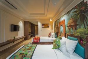 a hotel room with two beds and a tv at Tripli Regalia Mayur Palace in Udaipur