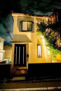 a yellow house with a black door on a street at Nomachi Villa in Kanazawa