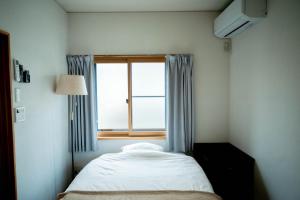 a small bedroom with a bed and a window at Nomachi Villa in Kanazawa