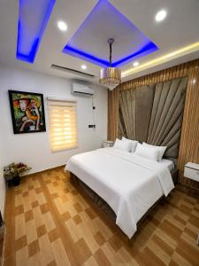a bedroom with a large white bed and a blue ceiling at Hog Inn Hotel in Benin City