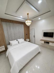 a bedroom with a large white bed and a chandelier at Hog Inn Hotel in Benin City