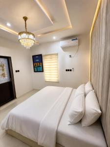 a bedroom with a large white bed and a chandelier at Hog Inn Hotel in Benin City