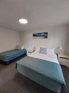 a hotel room with two beds and two tables at Bayview Motel in Paihia