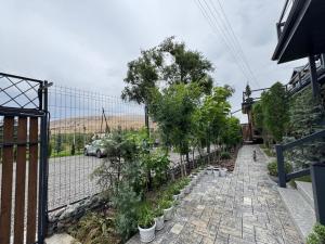 a garden with trees and plants on a sidewalk at Zarechnoe Guest House in Tash-Tyube