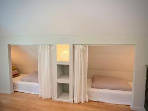 two beds in a room with white curtains at Lejnieki Apartment 4 in Pape