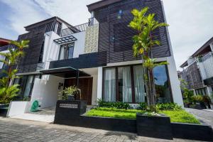 a black and white house with palm trees in front at Norm Villa Kuta in Kuta