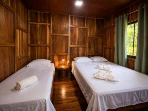 two beds in a room with wooden walls at House Rio Celeste Paradise in Rio Celeste