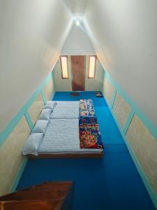 a small bed in a room with blue floors at Sabda Desa Cabin in Cinyiruan