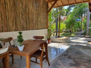 a room with a wooden table and chairs and a patio at G Two Cottages in Gili Islands
