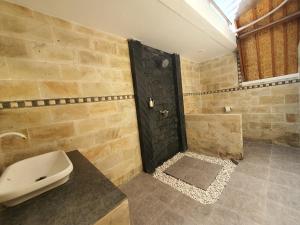 a bathroom with a toilet and a shower with a black door at G Two Cottages in Gili Islands +15 photos
