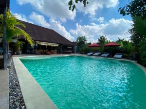 a swimming pool with blue water in front of a house at Maso Christian Villa Canggu in Tumbak Bayuh