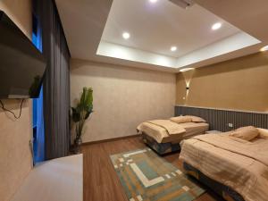 a bedroom with two beds and a flat screen tv at AL-Yasmin in Surabaya