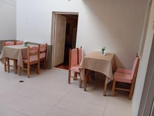 a dining room with two tables and pink chairs at Abril Hostel in Mollepata