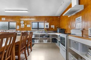 a kitchen with wooden walls and a table and chairs at Manowhenua Lodge Hostel in National Park