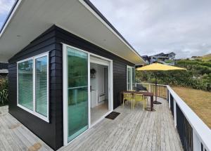 a house with a deck with a table and an umbrella at Tohora View in Waihi Beach +3 photos