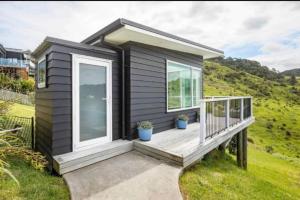 a tiny house with a porch and a deck at Tohora View in Waihi Beach