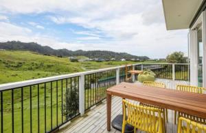 a balcony with a wooden table and yellow chairs at Tohora View in Waihi Beach