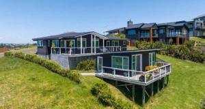 a large house on top of a grassy hill at Tohora View in Waihi Beach