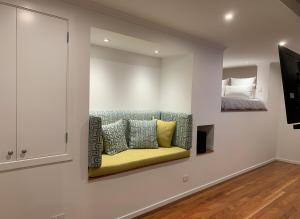 a living room with a yellow couch on a wall at Tiny house in the Treetops in Northland