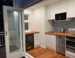 a kitchen with white cabinets and a glass door at Tiny house in the Treetops in Northland