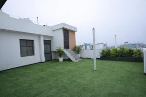 a white house with a yard with green grass at Hotel Almora Suites - Near Delhi Airport in New Delhi