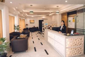 a woman standing at a counter in a lobby at Hotel Almora Suites - Near Delhi Airport in New Delhi