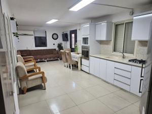 a kitchen and living room with white cabinets and a couch at באוירה יהודית in H̱azon