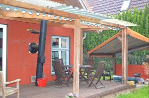 a wooden pergola with a table and chairs on a deck at Ferienhaus am Schulsee in Mölln +3 photos