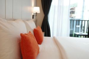 two orange pillows on a white bed with a window at Aree Tara Ao Nang Krabi in Ao Nang Beach