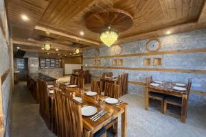 a restaurant with wooden tables and chairs and a chandelier at LN Grand Premium & Luxury Suites, Manali in Manāli