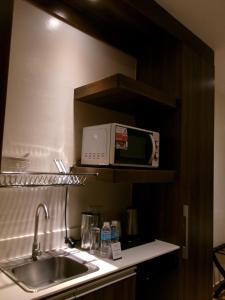 a kitchen with a sink and a microwave on a shelf at Alasra Suites in Ulot