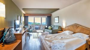 a bedroom with a bed and a desk with a television at Activehotel Diana in Siusi +54 photos