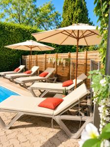 a row of lounge chairs with umbrellas next to a pool at Hotel Cayrons Vence & St Paul de Vence in Vence
