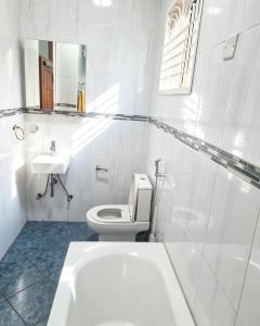 a white bathroom with a toilet and a sink at Deluxe unique homes kampala in Kampala +22 photos
