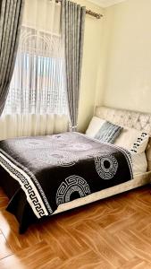 a bed with a black and white comforter and a window at Deluxe unique homes kampala in Kampala