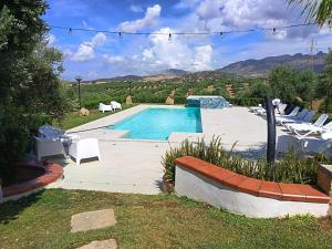 a swimming pool in a yard with chairs around it at B&B Le Foglie D'Argento in Caltabellotta