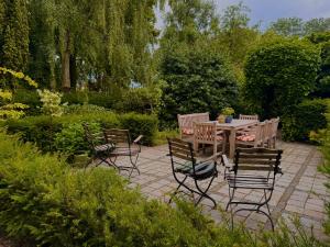 a patio with a table and chairs in a garden at Villa Abbekerk - Bed & Breakfast in Abbekerk