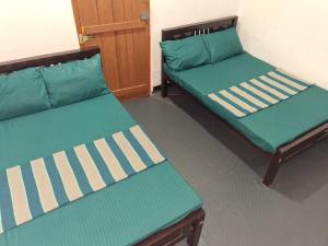 three beds in a room with green and white at New Guest in Nilaveli